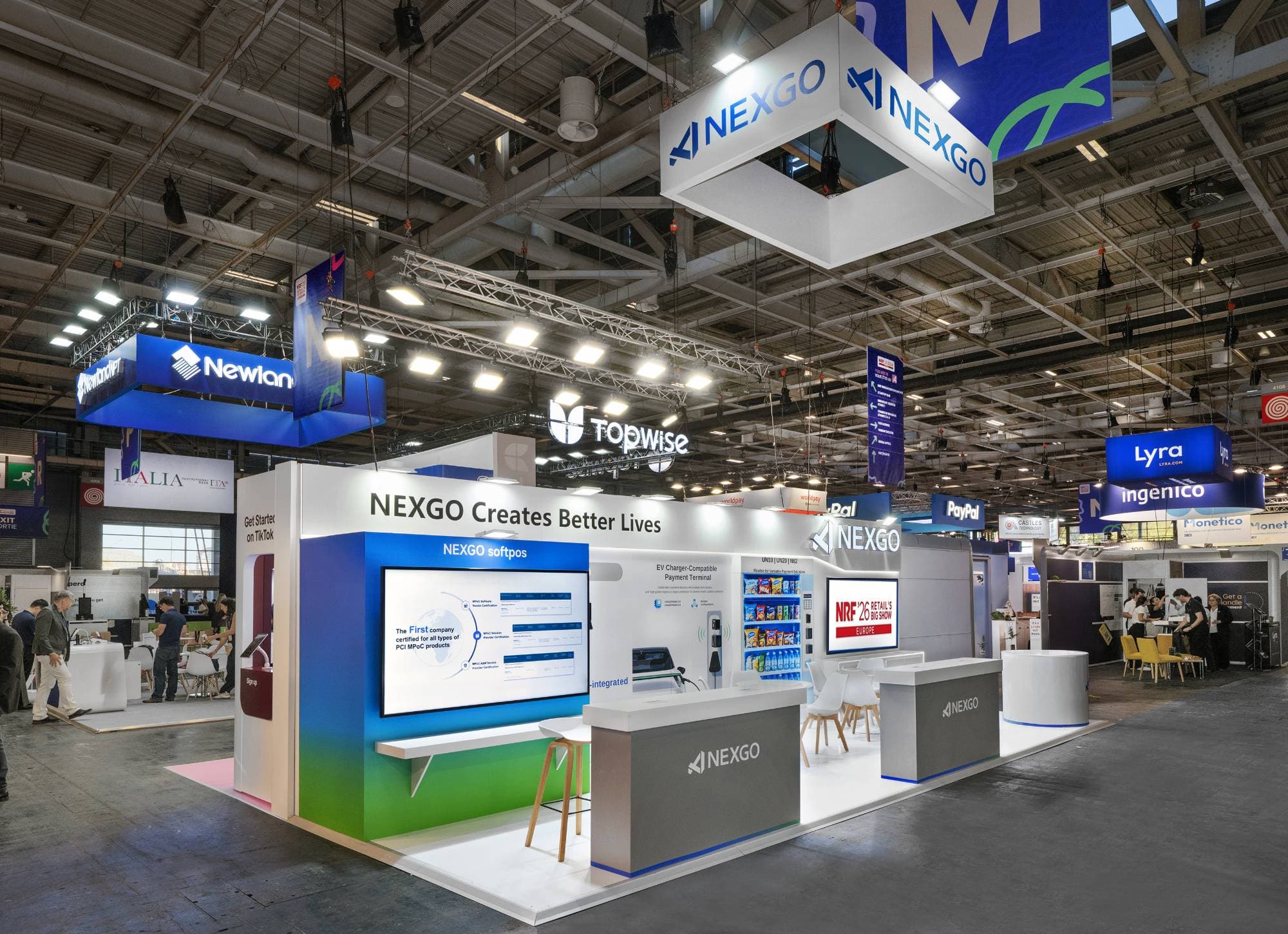 Stand NEXGO sur NRF Europe, Porte de Versailles : enseigne suspendue, mur de démonstration et comptoirs d'accueil