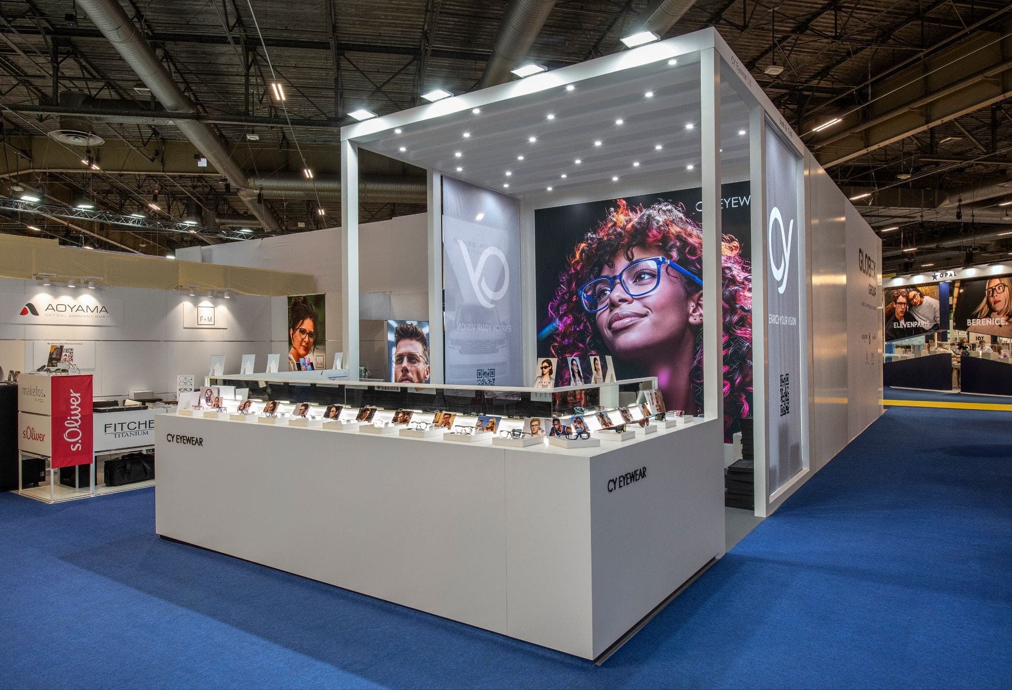 Stand CY Eyewear sur le Silmo : comptoir d'angle et vitrine éclairée de montures, plafond semé de spots, grand visuel de marque